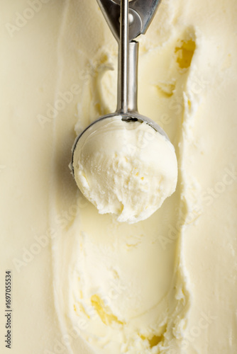 Принти на полотні Vanilla ice cream scoop in metal spoon over creamy background, macro food textur
