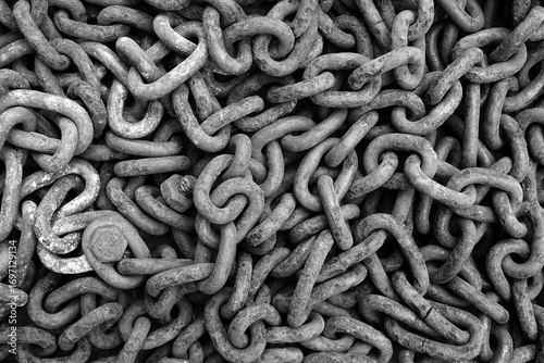 The grey old rusty, time-cracked chain from a ship, a boat consisting of many links lies on the floor