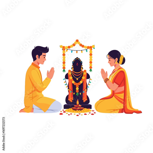 An Indian couple in traditional yellow attire praying to a Hindu deity statue during a puja ceremony.
