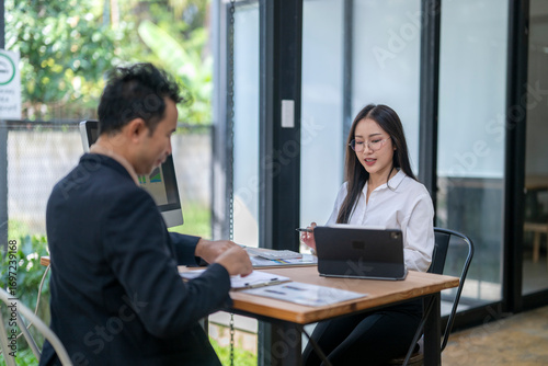 Business people working together in modern office analyzing charts and reports on computer and tablet