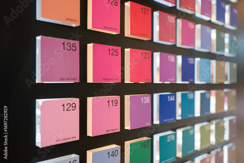 Color swatch display with neatly arranged square tiles showing various shades, each labeled with its name and number on a black background.