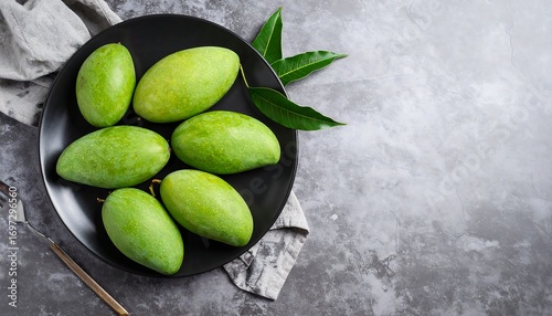 Green mangoes on a black plate