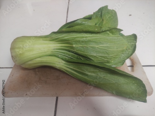 Fresh bok choy placed on wooden cutting board, close-up photo of healthy Asian leafy green vegetable