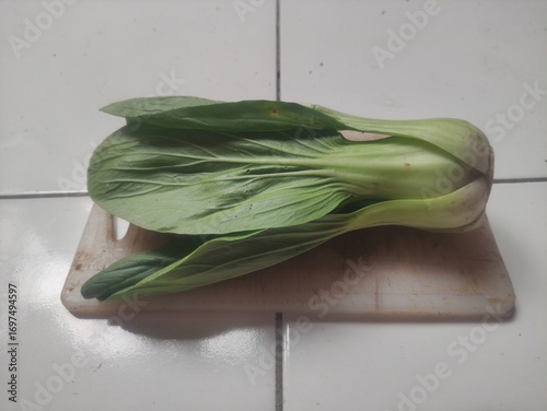Fresh bok choy placed on wooden cutting board, close-up photo of healthy Asian leafy green vegetable