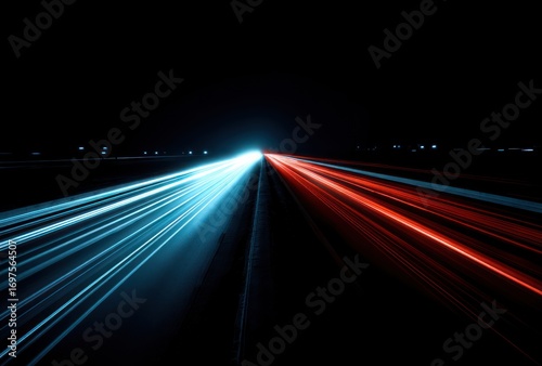 Abstract time-lapse view of road, streaks of blue & red light trailing from headlights on dark asphalt. Blurred motion