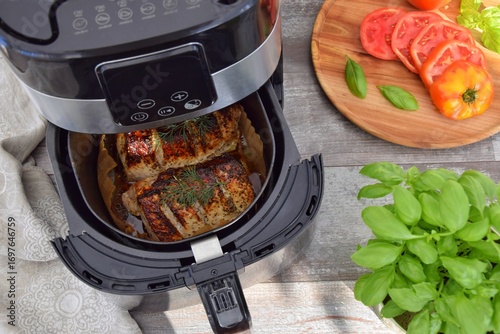 Meat cooked in a deep fryer. On the table are sliced ​​tomatoes and basil.