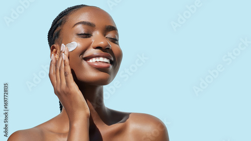Overjoyed African American young woman with afro braids hairstyle is applying cosmetic product on her face Skin care beauty portrait. Cream smear. Hydration, nourishing and moisturising.