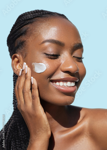 Happy Skin care beauty portrait. Cream smear. Hydration and oil balance. Nourishing and moisturising. African American young woman with afro braids hairstyle is applying cosmetic product on her face