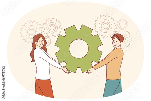 Teamwork of industrial employees together holding gear from production mechanism. Teamwork of man and woman demonstrating trusting partnership and ability to work in team, achieving synergy
