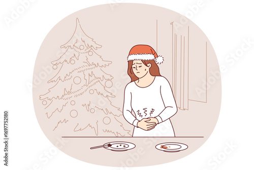 Stomach pain caused by overeating at christmas dinner plagues woman in need of medication. Stomach cramps in girl standing near new year table and christmas tree, after poisoning with low-quality food