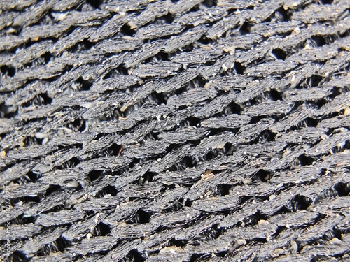 A detailed macro shot of a used mouse pad's surface, revealing a rough, woven texture with visible dirt and dust particles. The abstract pattern is perfect for technology, gaming