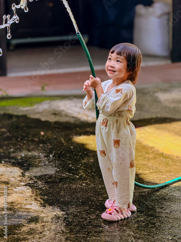 Girl outdoor activity. Children playing water outdoor with happiness in pajamas on sunny day 