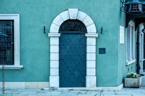 Historic, old metal door with an arched portal in a tenement house with a green facade