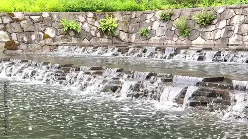 Water flowing over rocks in the park. Small stepped waterfall outdoors. Meditation video