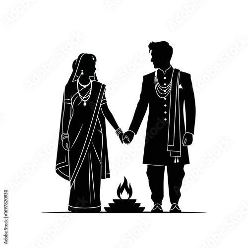 Silhouette of a bride and groom holding hands during a traditional Indian wedding ceremony with a sacred fire.
