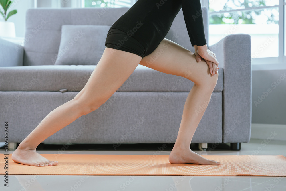 Obraz premium A young woman in black sportswear stretches gracefully indoors with eyes closed, focusing on relaxation, flexibility, wellness, and mindful breathing.