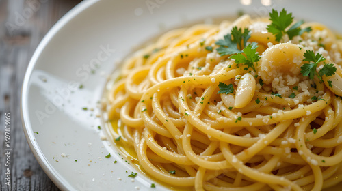 Close-up shot of a plate of spaghetti aglio e olio, a classic Italian pasta dish, garnished with parsley and garlic.