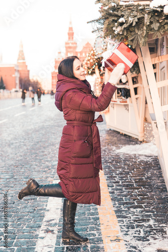 Photography Woman wearing a warm red coat and white mittens adjusting Christmas tree ornaments