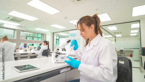 Wallpaper Mural Researcher examines samples under microscope in modern laboratory setting during daytime Torontodigital.ca