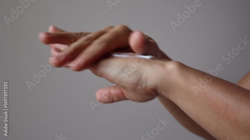 Lady rubs nourishing cream anti-aging effect on hands skin. Woman smears hands with nourishing product improve skin