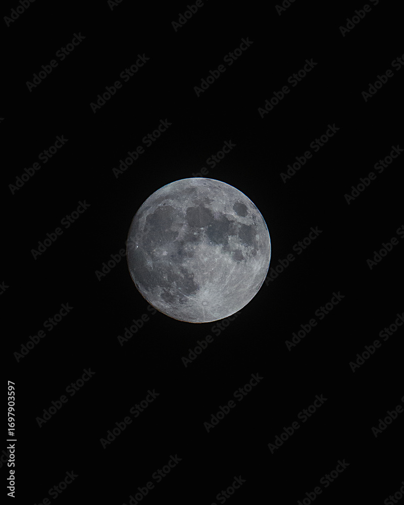 Fototapeta premium A detailed image of the full moon, focusing on its surface with clearly visible craters and texture. The photo was taken against a dark night sky, the naturalness of the Earth's satellite