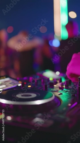 DJ mixing music at a party with turntable, blurred crowd, and bright colorful neon lights