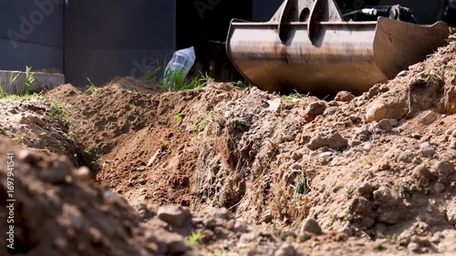 Excavator bucket filling trench with soil