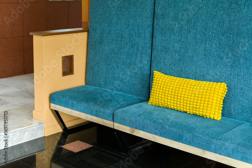 Modern interior design featuring comfortable teal bench with bright yellow cushion. Stylish furniture for contemporary waiting area, lobby, or home. quiet, simple seating concept