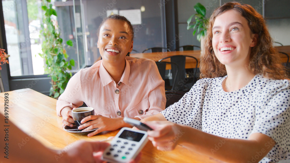 Fototapeta premium Woman In Coffee Shop Paying Bill With Contactless Mobile Phone Payment