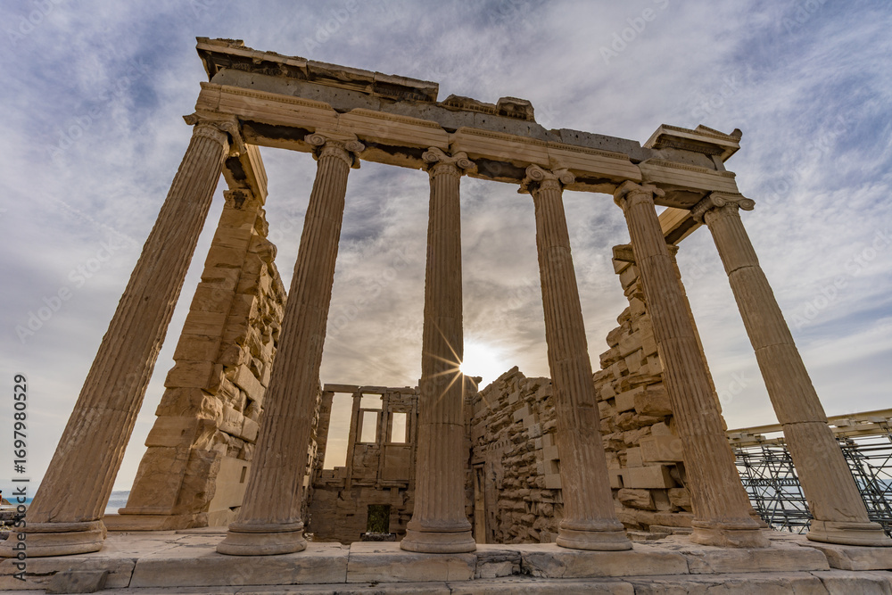 Obraz premium The Erechtheion temple on the Acropolis of Athens with sunburst behind marble columns, Greece.