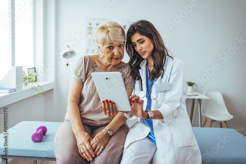 Photos Doctor Consulting Elderly Patient Using a Tablet in a Modern Clinic