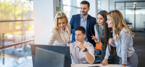 Business team collaborating on project around computers during office meeting
