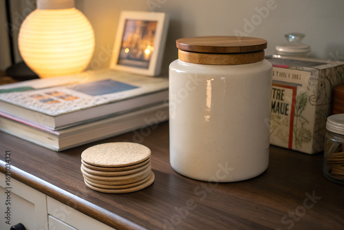 Neutral home interior detail with ceramic jar, wooden lid, round coasters and soft ambient lighting perfect for minimalist lifestyle visuals, cozy decor and product styling scenes