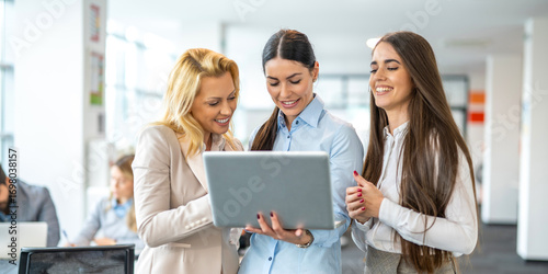 Foto Three businesswomen of different ages discussing business on laptop in office