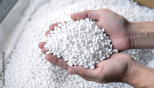 Hands holding a pile of white plastic pellets