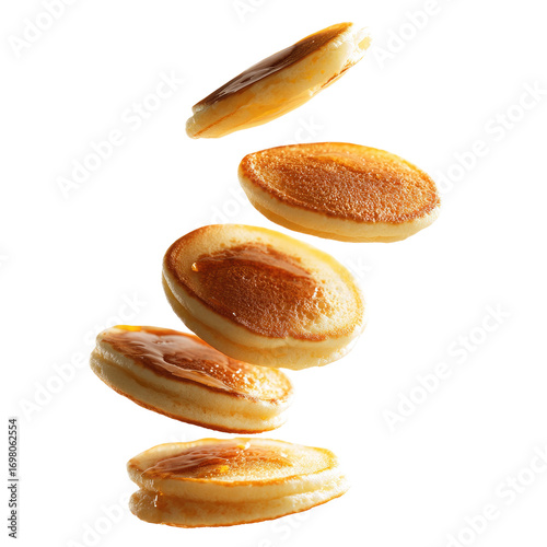 Mini pancakes in mid-air, golden brown, slightly glazed