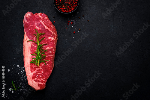 Bild auf Leinwand Delicious raw picanha beef steak from marbled beef with a fat cushion from the rump cut with rosemary and pepper, black background