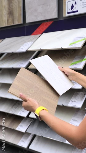 Hands holding ceramic tiles in hardware store comparing options for renovation