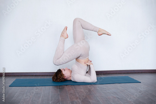 Beautiful girl practices kundalini yoga indoors in daylight.