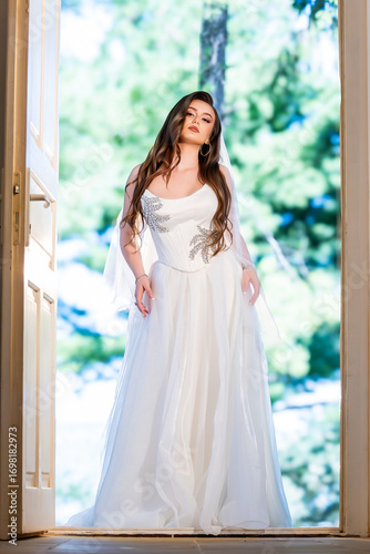Free Download Bride in elegant white wedding dress posing in front of historic mansion - GFXLoad