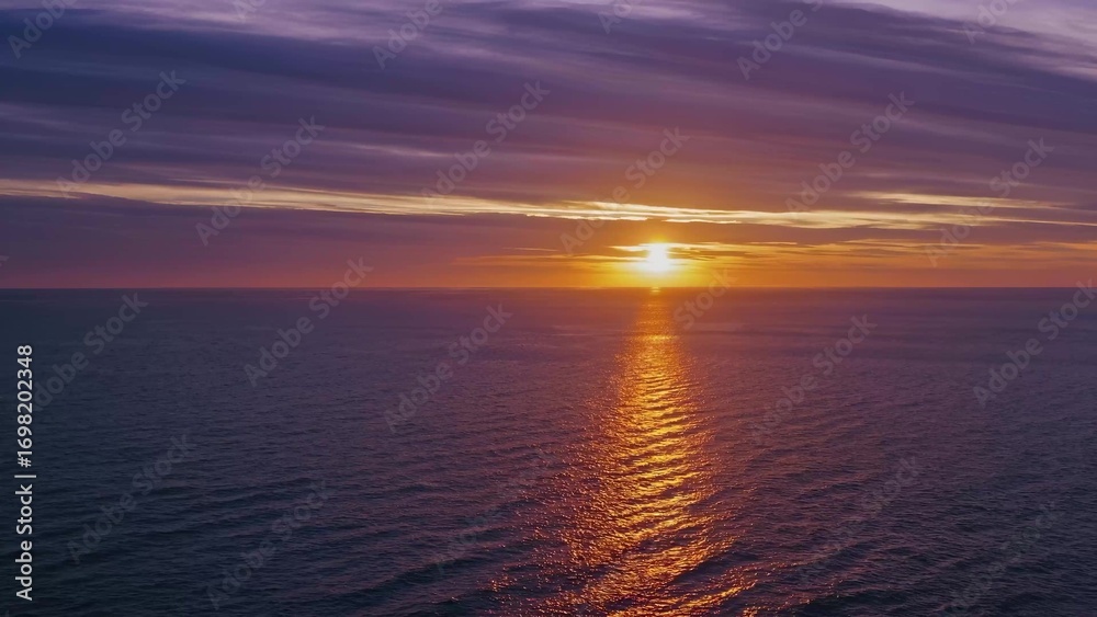 Fototapeta premium Sunset over ocean. A sunset over horizon with a calm ocean. Beautiful reflections of the sky in the evening. The sunset above the sea lifestyle.