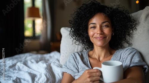 Woman Sitting on Couch with Coffee Mug in Cozy Bedroom Relaxing and Smiling with Soft Natural Light