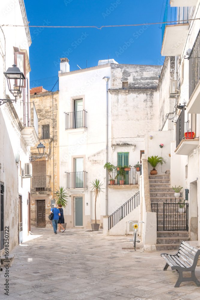 Obraz premium A shot of buildings among stone alleys and Mediterranean balconies in the historic center under a blue sky, Southern Italy. Grottaglie is a ceramics city.