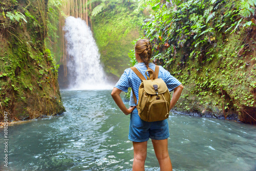 Female tourist with backpack enjoying view of awesome waterfall