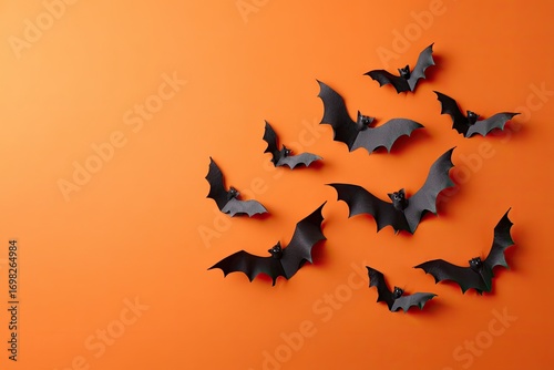 Spooky black bat decorations scattered on a vibrant orange Halloween background.