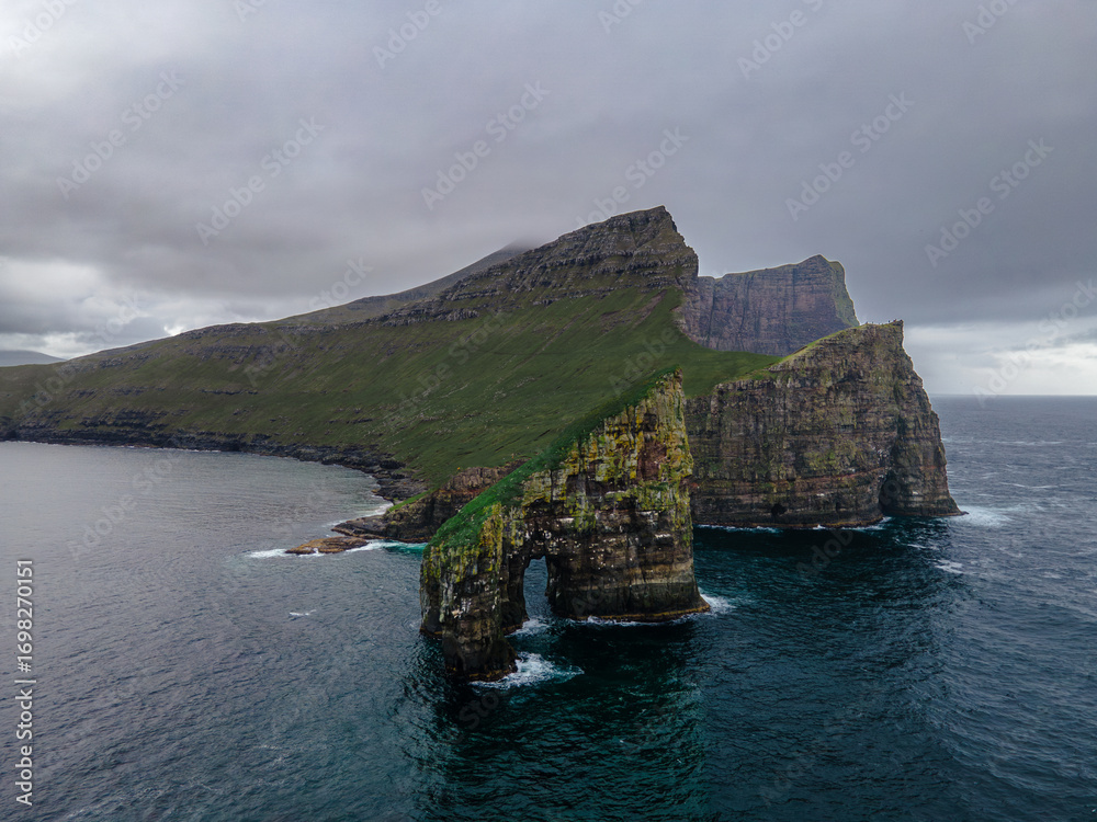Fototapeta premium Drone view of Drangarnir cliff with Tindholmur islands in the background during early morning hike