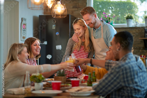 Hugged Caucasian couple watching group of friends having a toast .