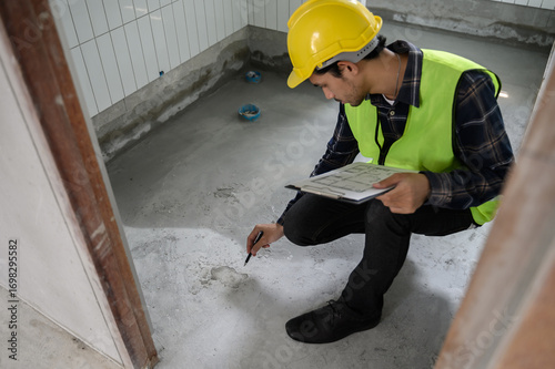 Engineer or inspector using blueprint check sheet examining cracked concrete floor during house construction. Quality control, building inspection, structural defect, real estate maintenance concept.