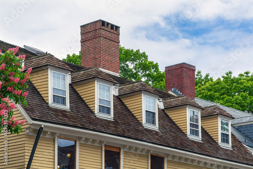Hipped dormer windows and aged shingle roof gracing a traditional residential home exterior in Cambridge, Massachusetts, USA
