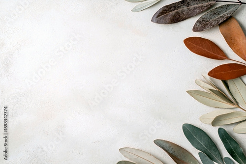 Dry brown and green leaves on light textured stone background with copy space on the left